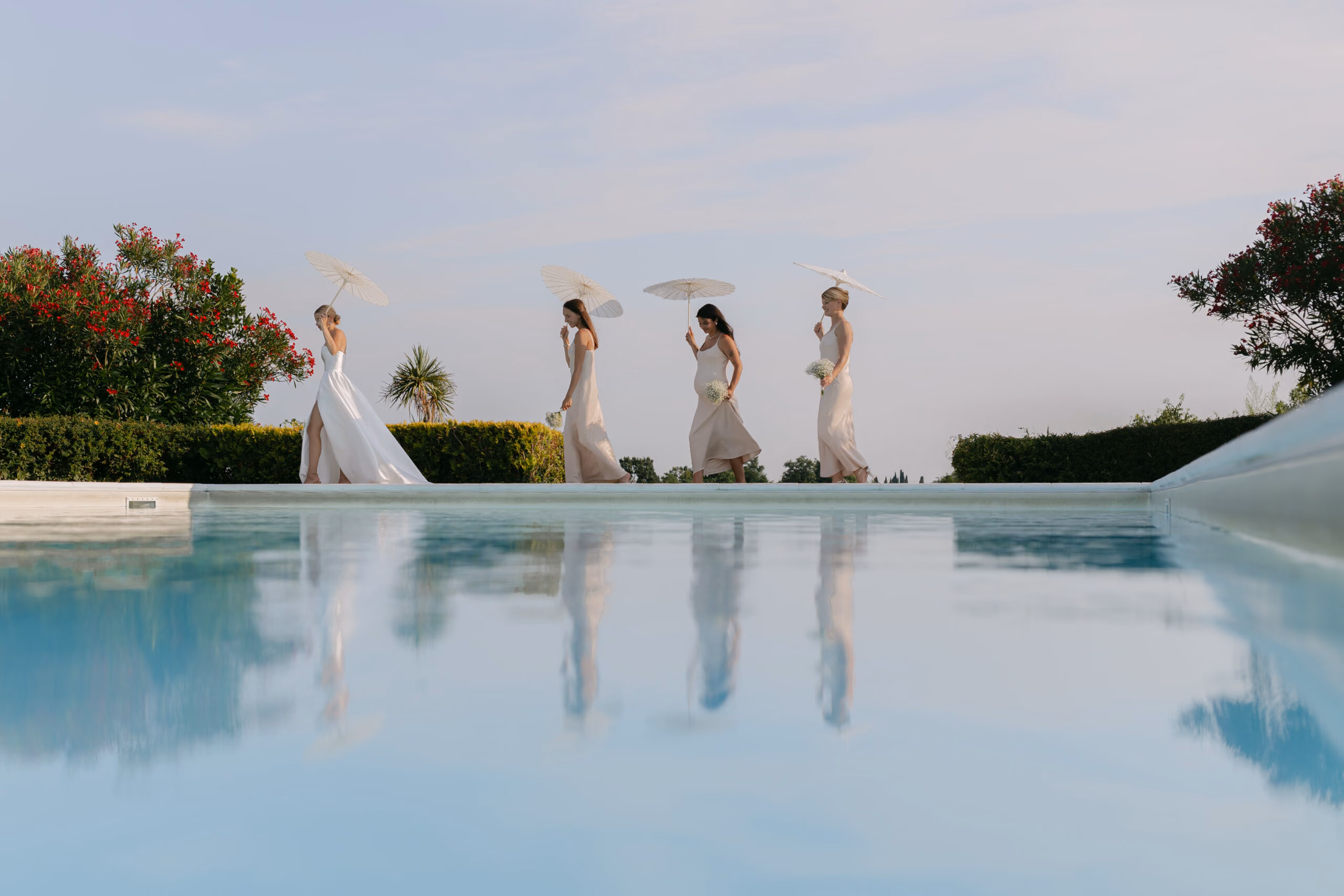 Brautjungfern spiegeln sich im Pool einer Hochzeitsvilla in der Toskana